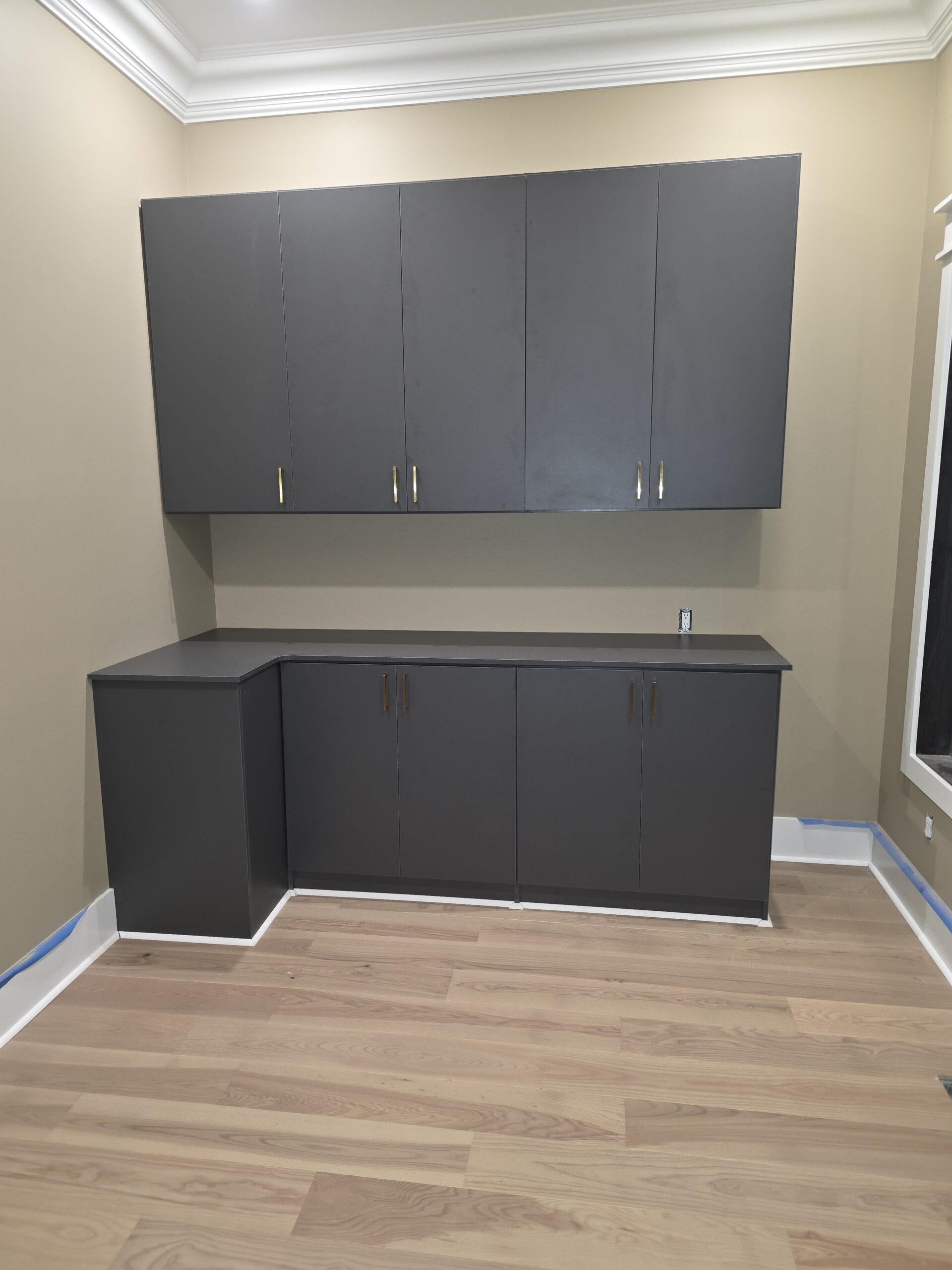 Modern gray storage cabinets installed in a corner room with light wood flooring.