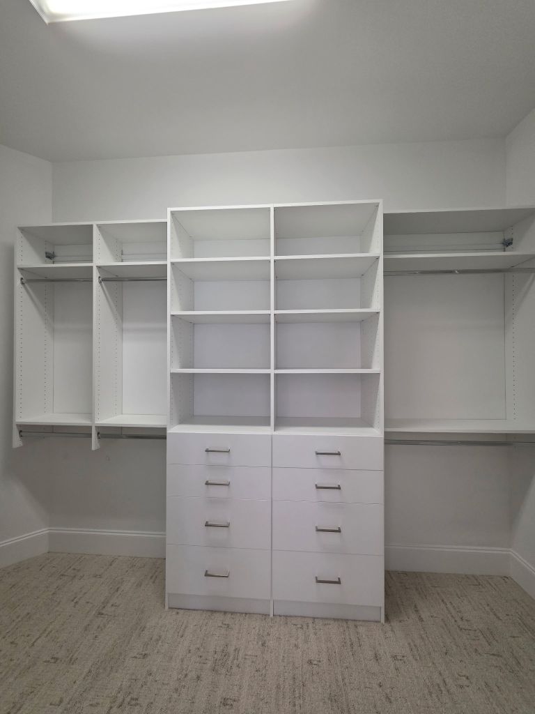 A modern white walk-in closet with shelves and drawers.