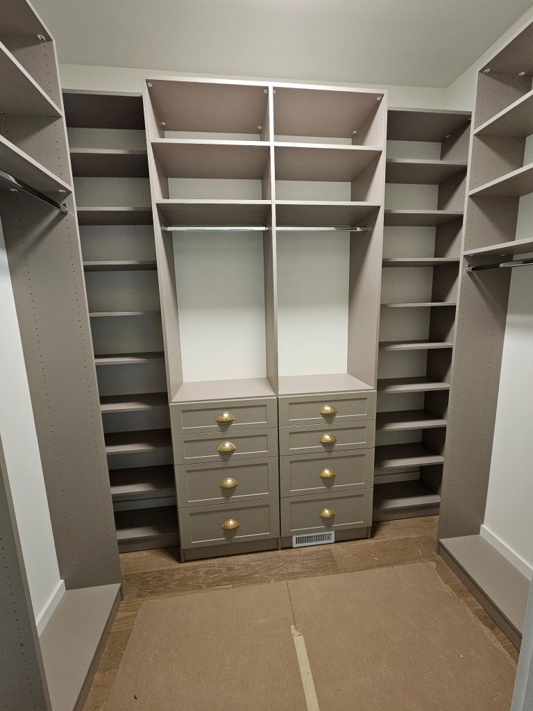Empty walk-in closet with shelves and drawers.