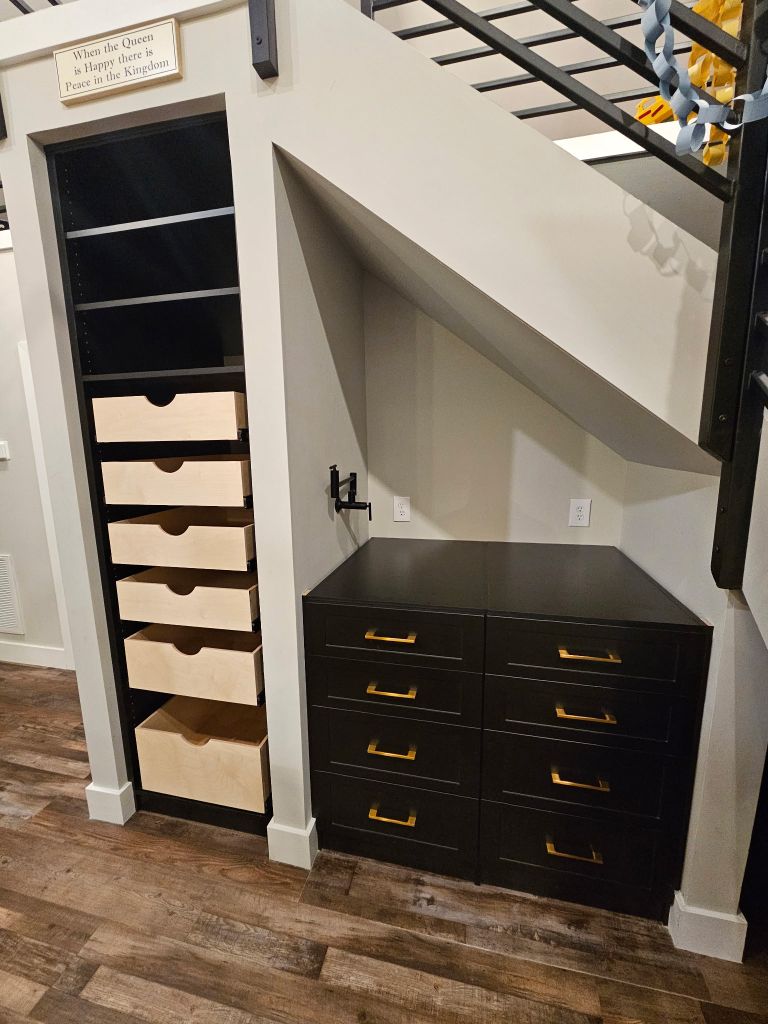 Custom storage unit with drawers and shelves under a slanted ceiling.