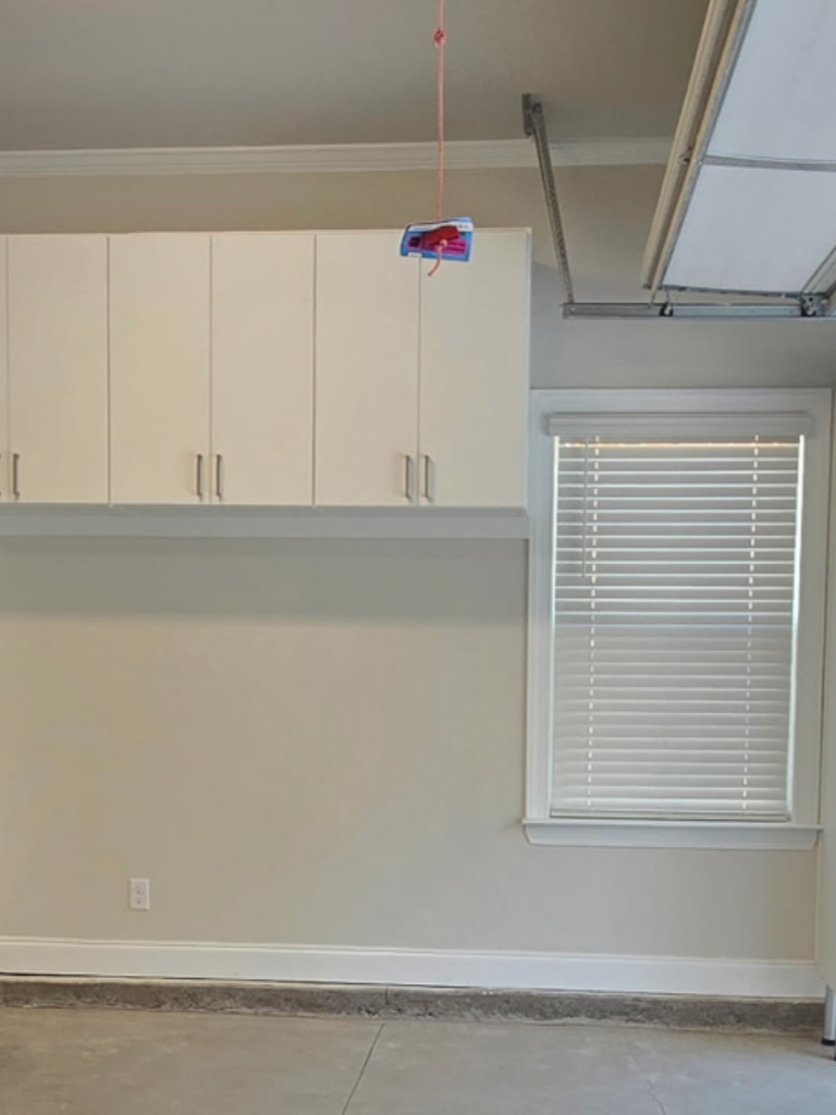 A small drone flying indoors near a window and cabinets.