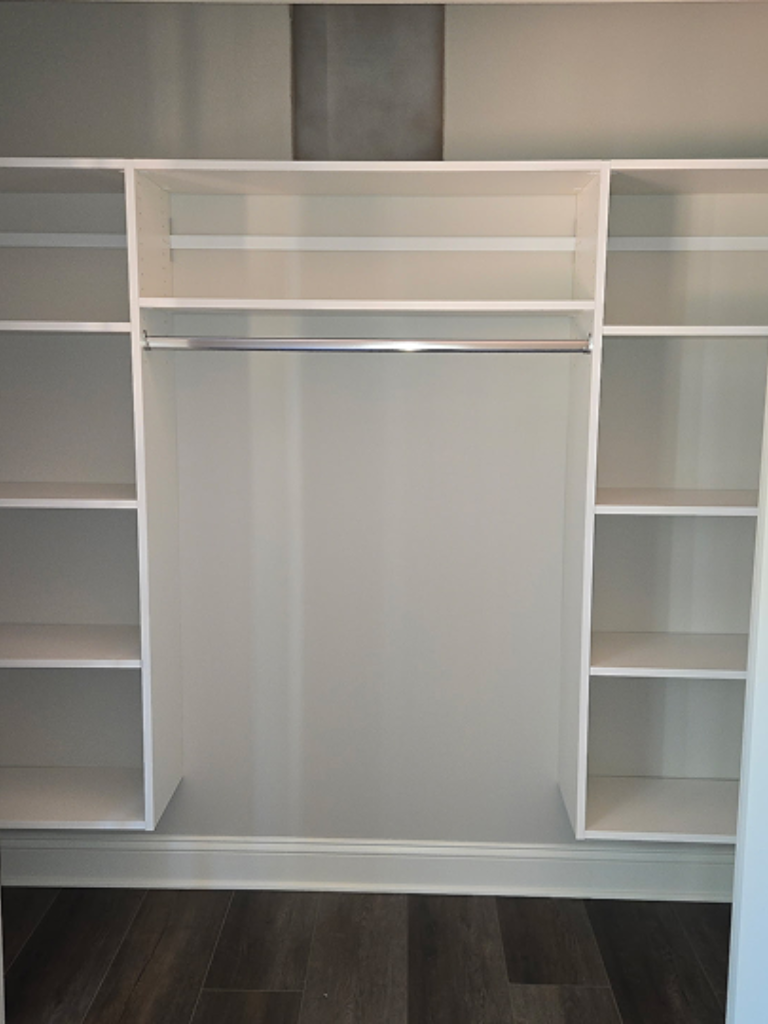 Empty white closet organizer with shelves and hanging rods.