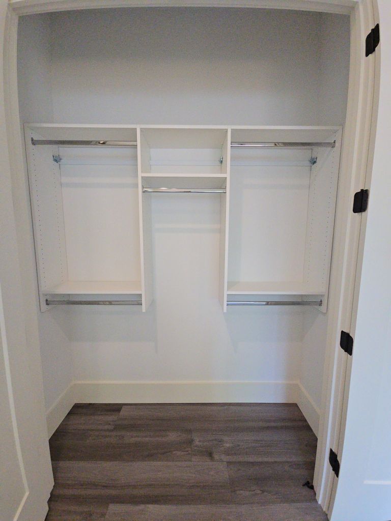 Empty modern closet with white shelves and hanging rods.
