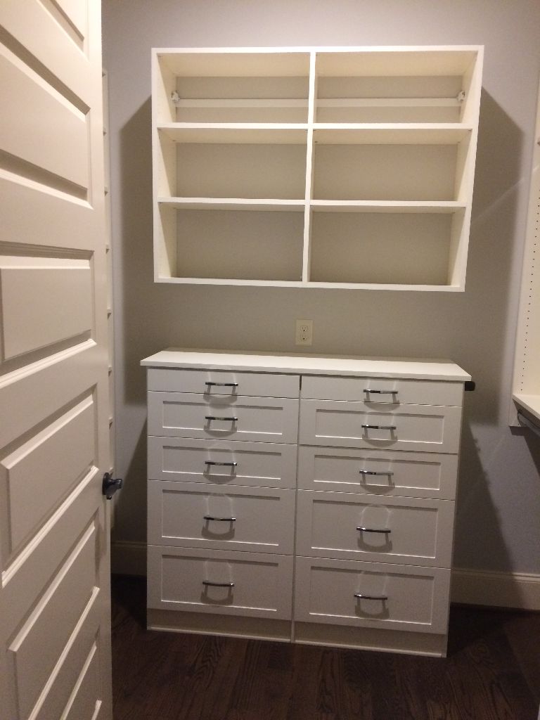 White dresser with multiple drawers and an empty wall-mounted shelf.