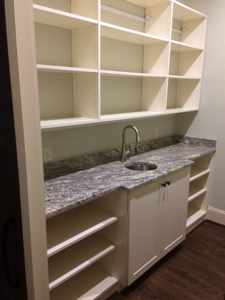 Empty kitchen shelves and sink with granite countertop.