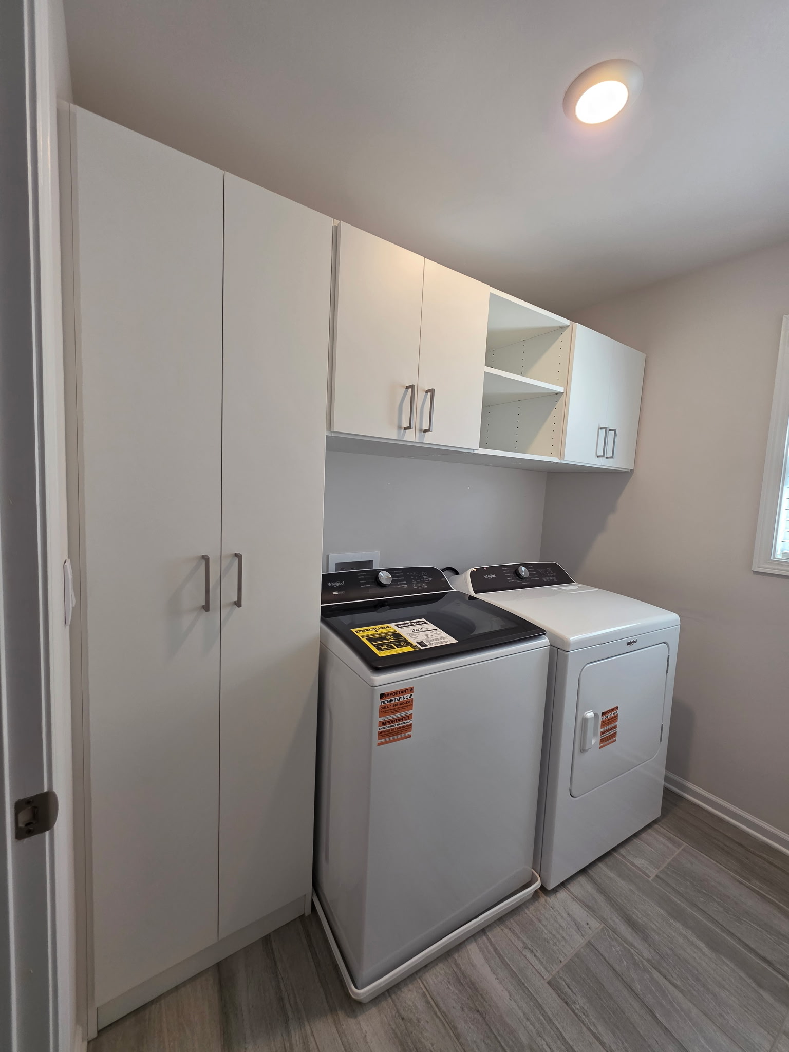 Modern laundry room with washer, dryer, and cabinets.