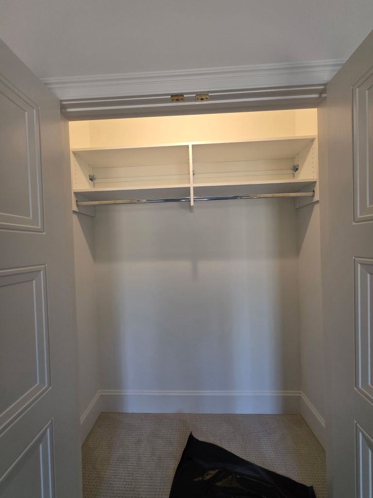 Empty closet with shelves and hanging rod.
