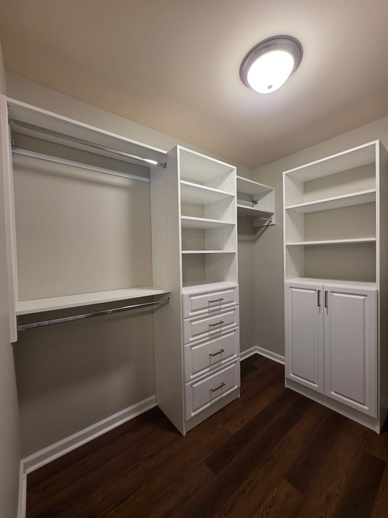 A spacious walk-in closet with white shelves and drawers.