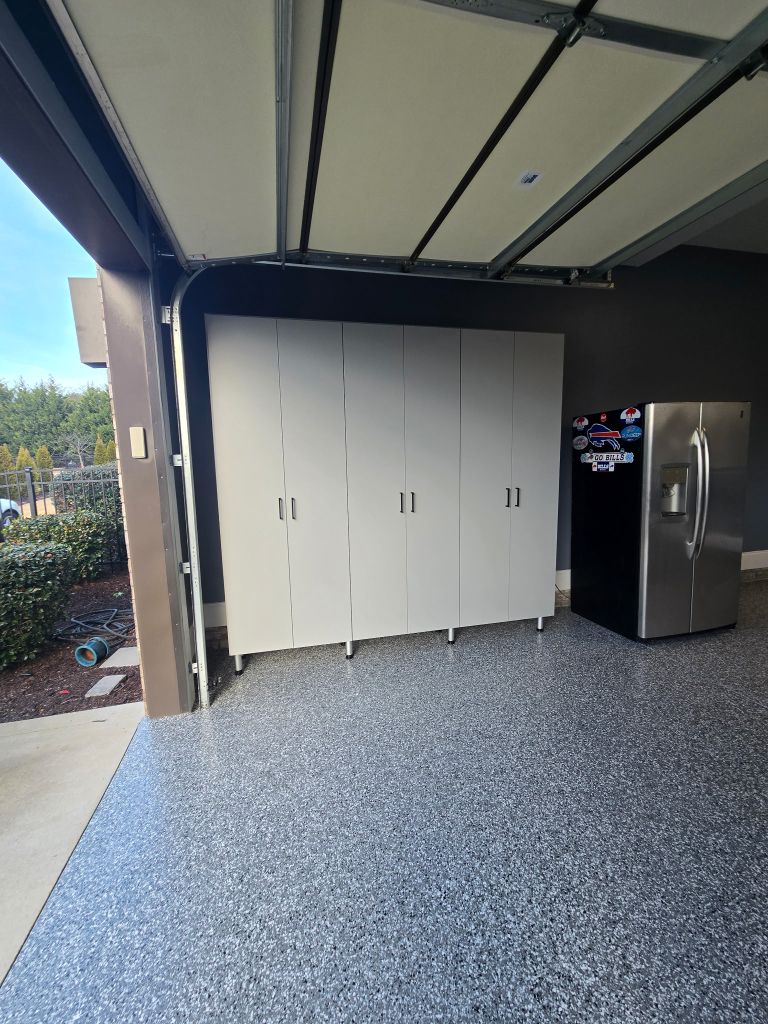 Three white storage cabinets and a refrigerator in a garage.