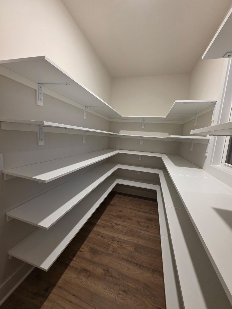 Empty white pantry shelves with wooden floor.