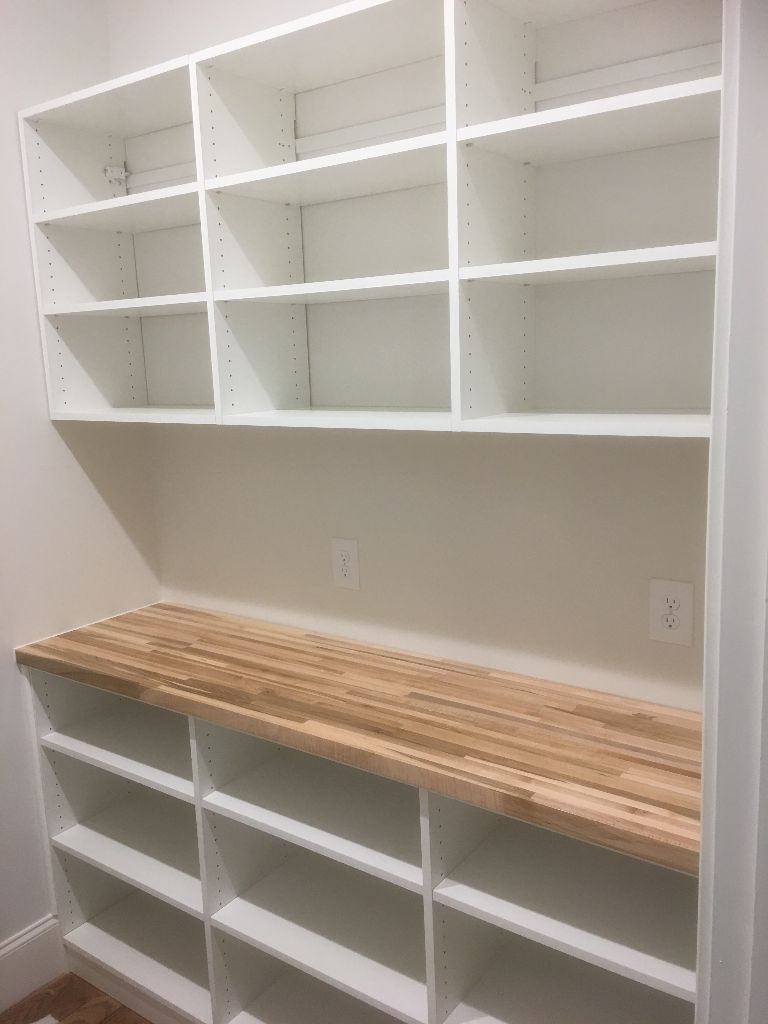 Empty white shelves with a wooden countertop in a clean room.