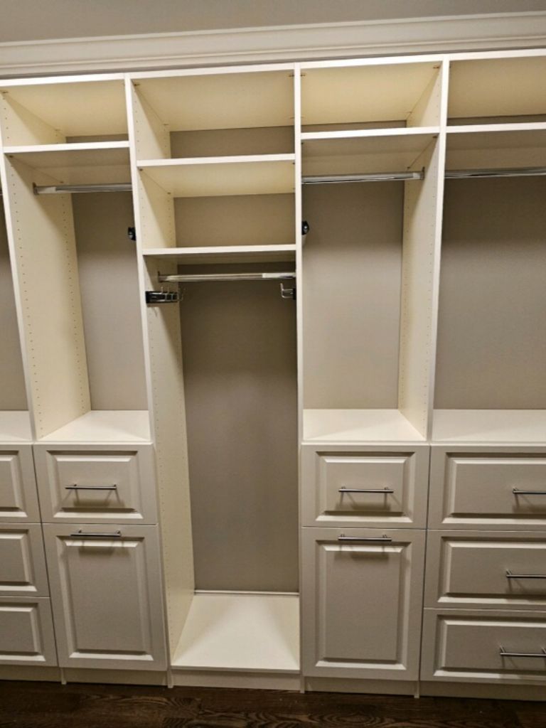 A spacious, empty walk-in closet with built-in shelves and drawers.
