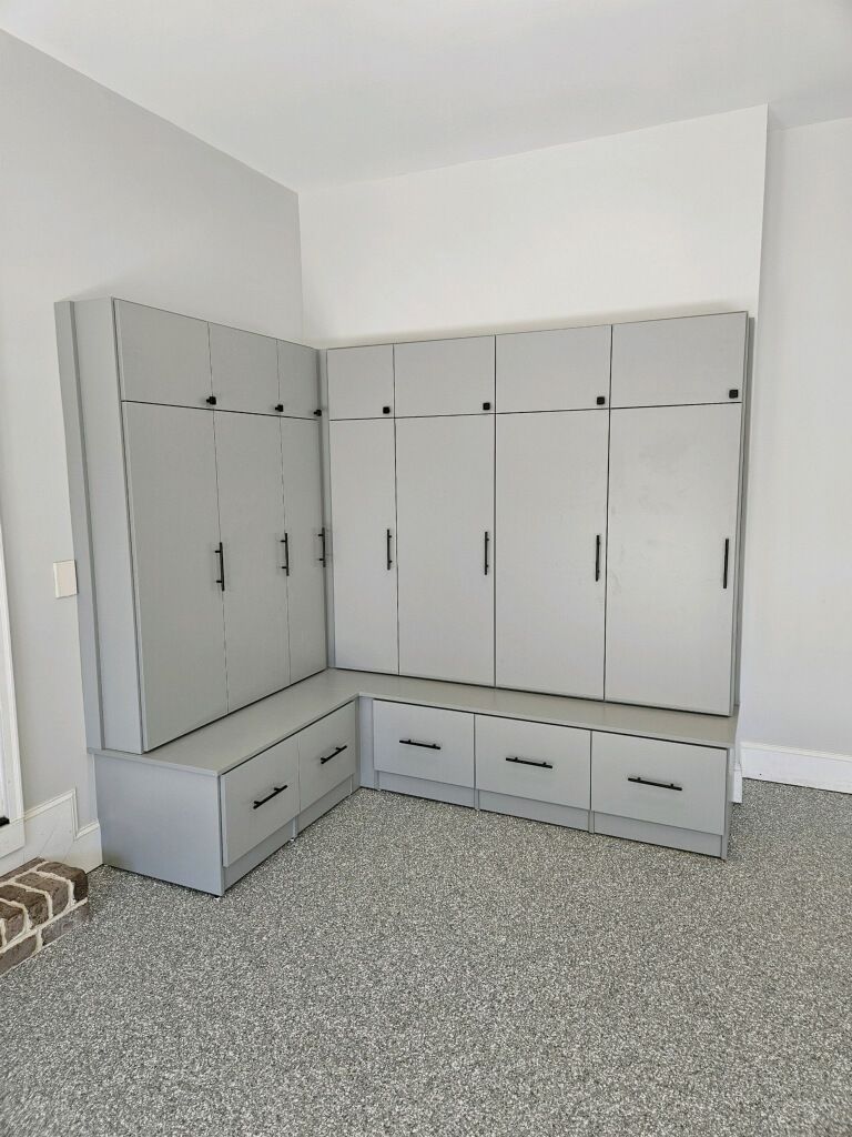 Modern gray corner storage unit with hooks and drawers.