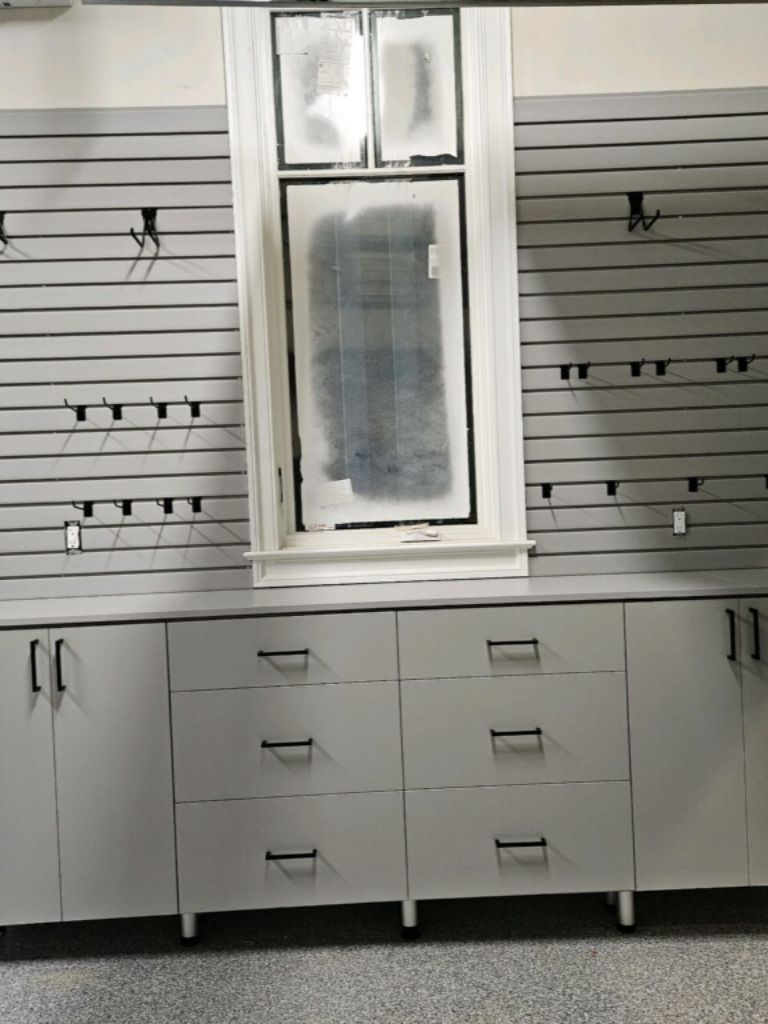 White cabinets and drawers with a window above in a modern room.