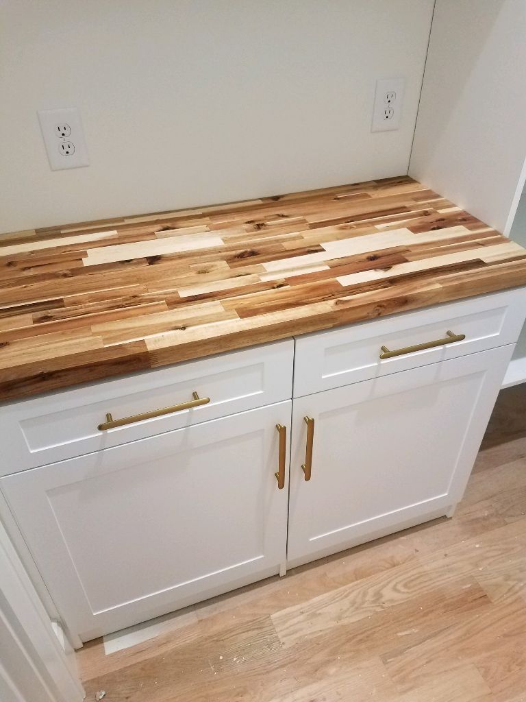 Modern kitchen cabinet with a wooden countertop and gold handles.