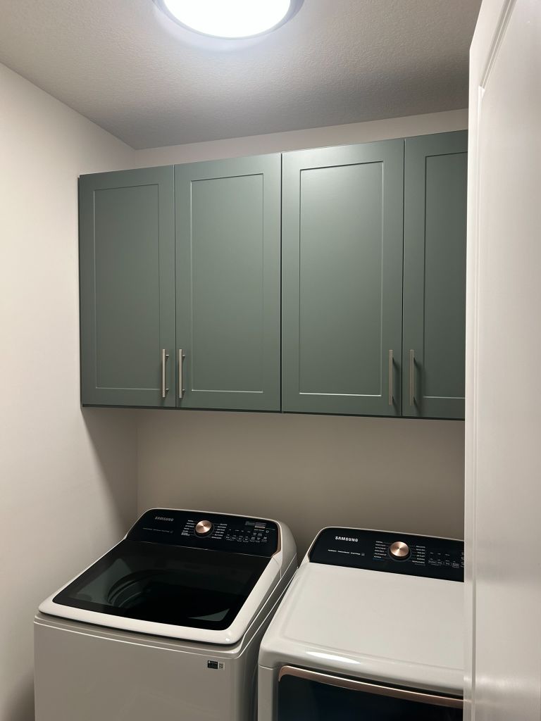 Laundry area with green wall cabinets above washer and dryer.