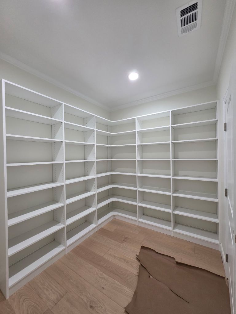 Empty white corner shelves in a bright room with wooden floor.