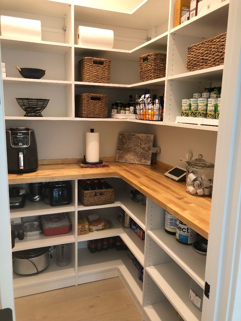 Organized pantry with wooden countertops and white shelves.