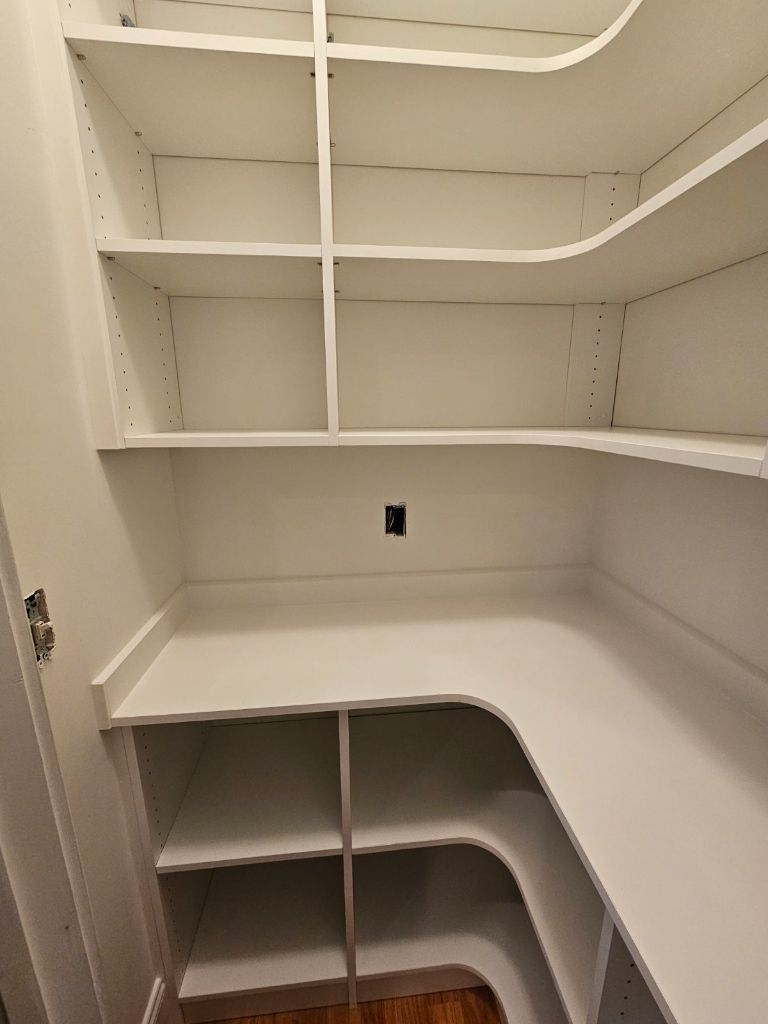Empty white pantry shelves with curved corners and lower storage compartments.