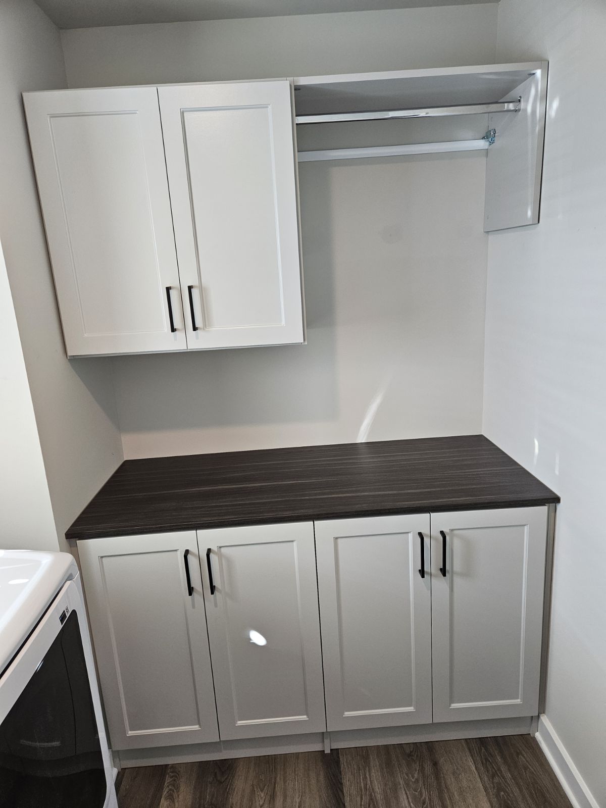 Modern kitchen cabinets with a dark countertop and white walls.