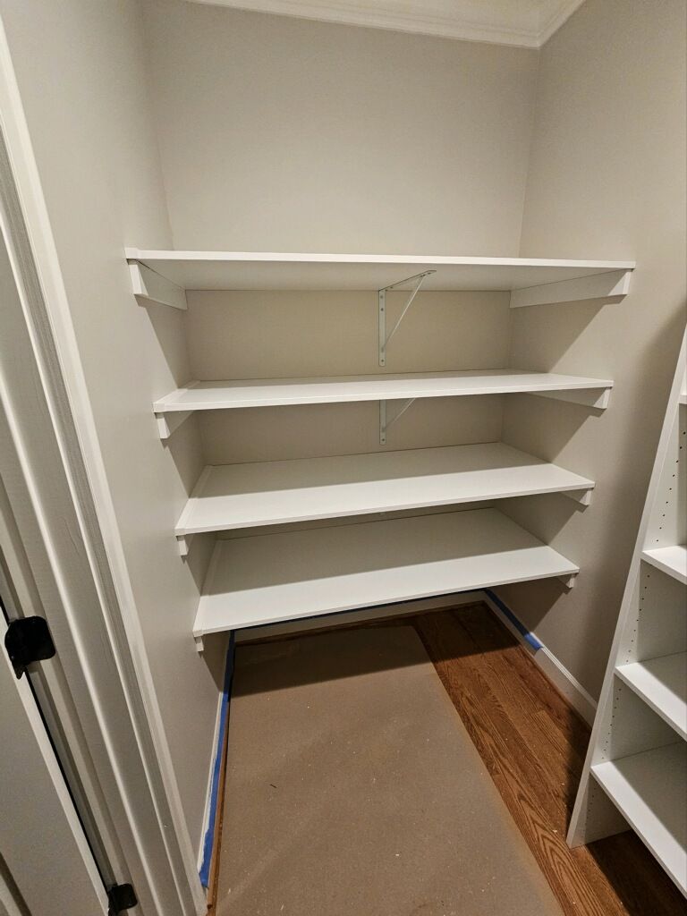 Empty white shelves installed in a small closet space.